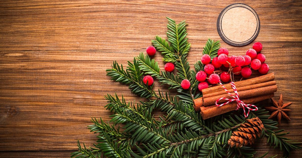 Warm holiday-themed flat lay with festive decorations including pine cones and berries on wooden background.